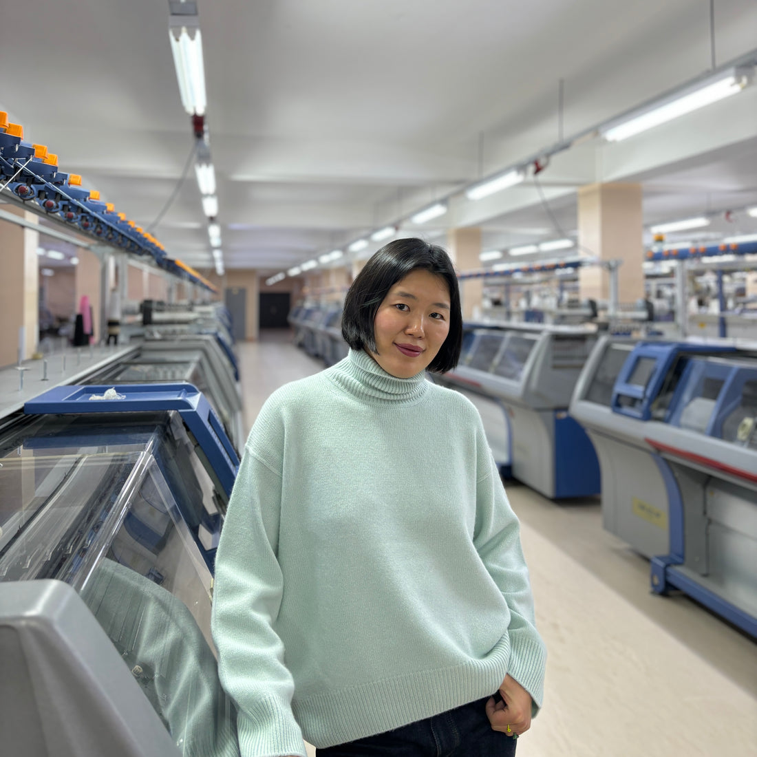 Mandkhai wearing an ice blue jumper in her brand's factory in Mongolia