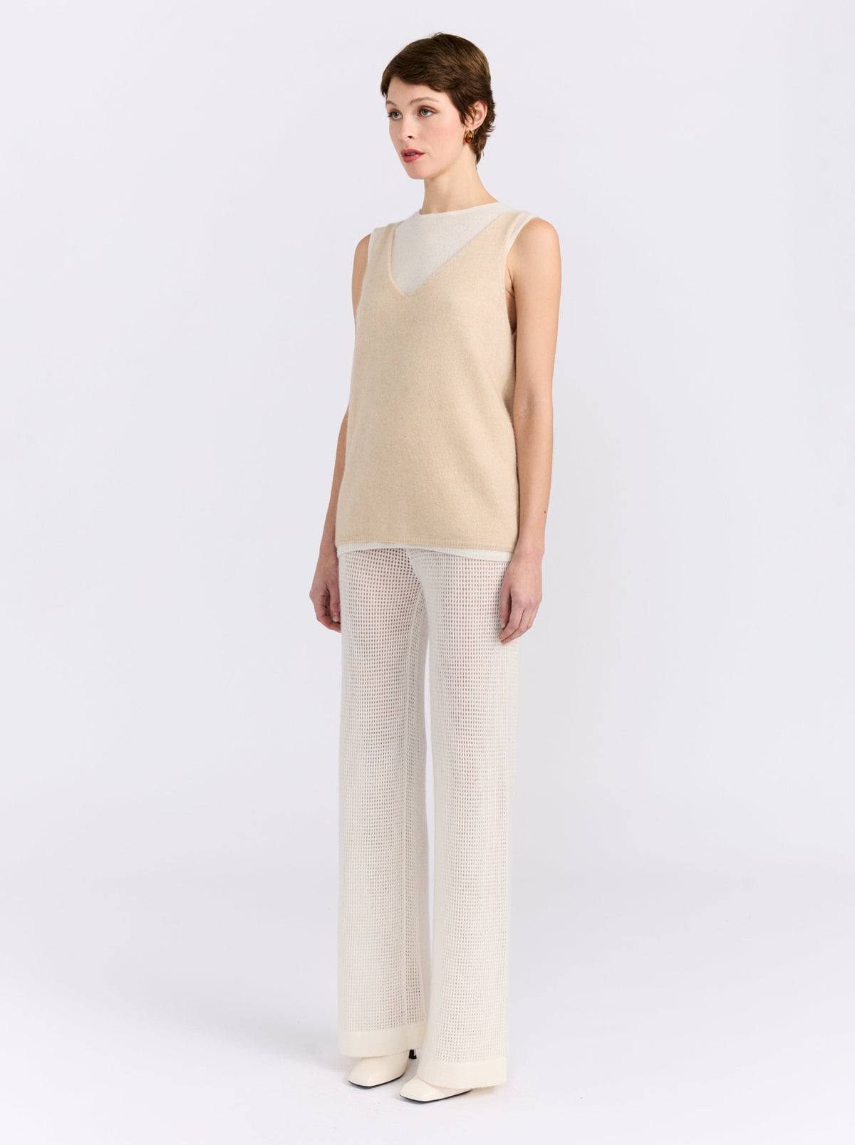 Side view model wearing the MANDKHAI beige and white double-layer cashmere vest with cream wide-leg trousers.