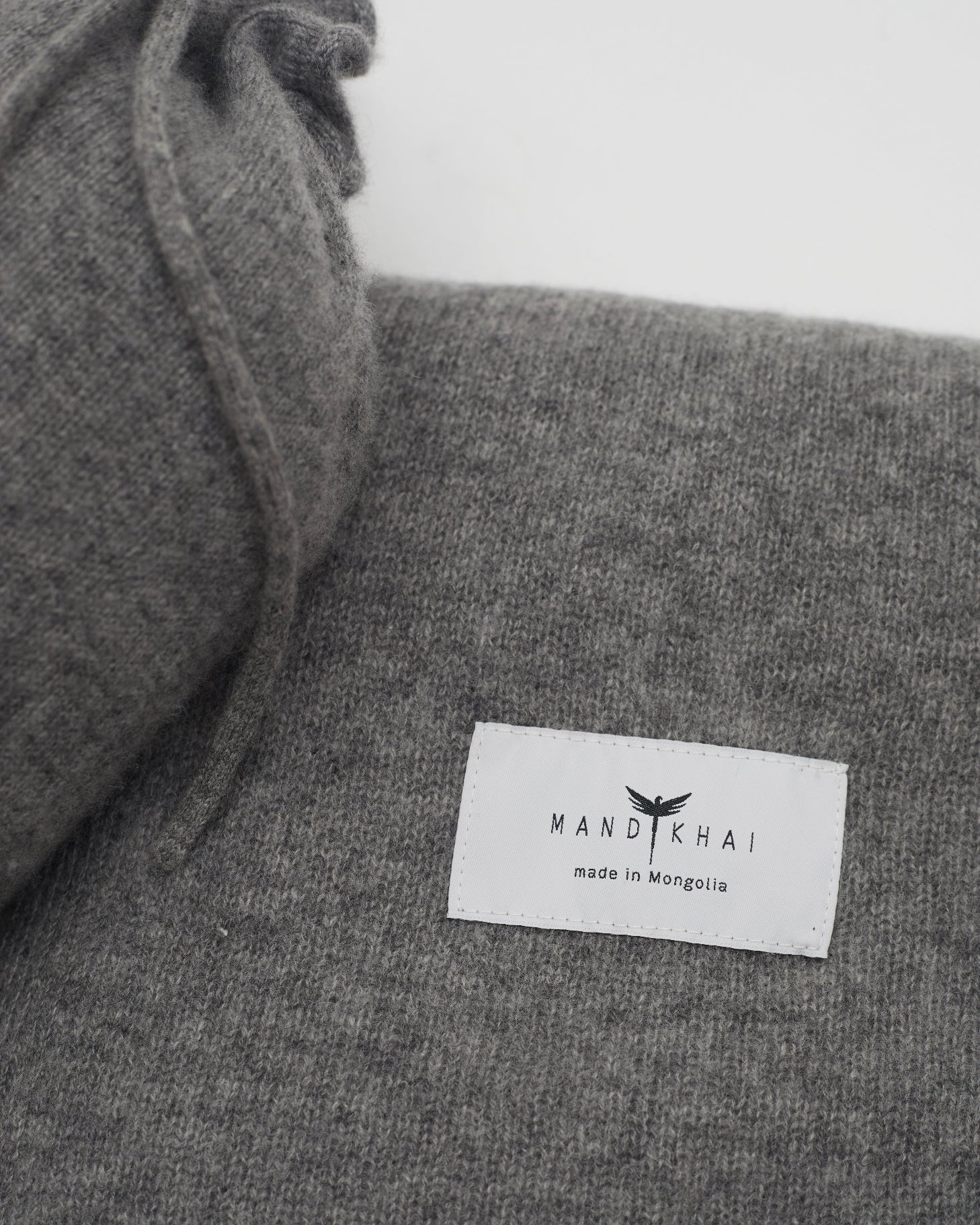Close up flat lay of the Grey Cashmere Shawl With Travel Pouch featuring Mandkhai's label and the lace detail of the travel pouch