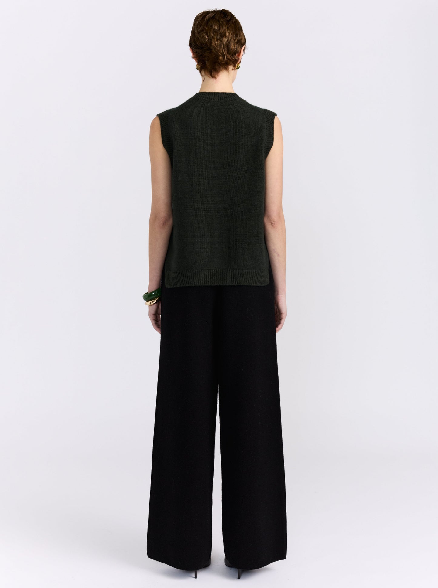Khaki cashmere vest with hand-embroidered floral detailing, styled with black wide-leg trousers.