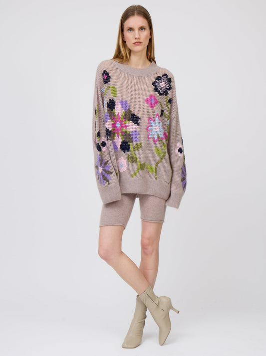Model wears beige cashmere net knit jumper, with round neck, long sleeves and bold cross-stitch floral embroidery; and worn with beige cashmere biker shorts.