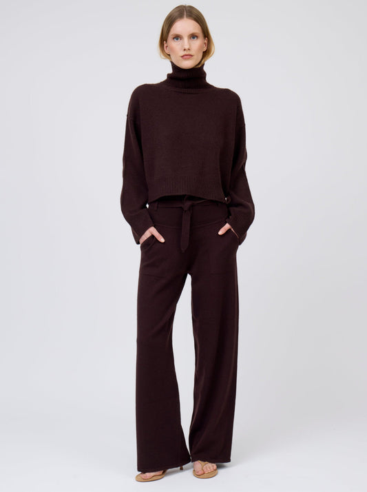 Model wears mahogany brown cashmere, wide leg pants with tie belt and pockets; worn with matching mahogany brown  cashmere, cropped length, roll-neck sweater.