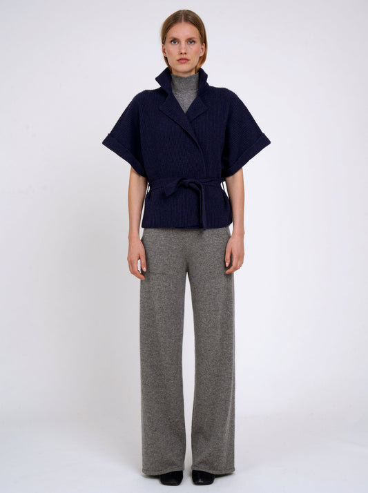 Front view model wears navy cashmere short ribbed knit jacket with grey wide leg pants.