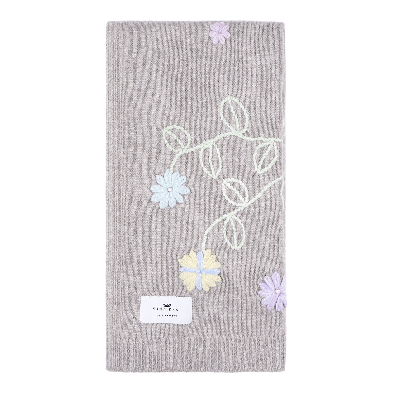 Beige knitted cashmere, square baby cost blanket, covered in pastel coloured hand embroidery of flowers and leaves.