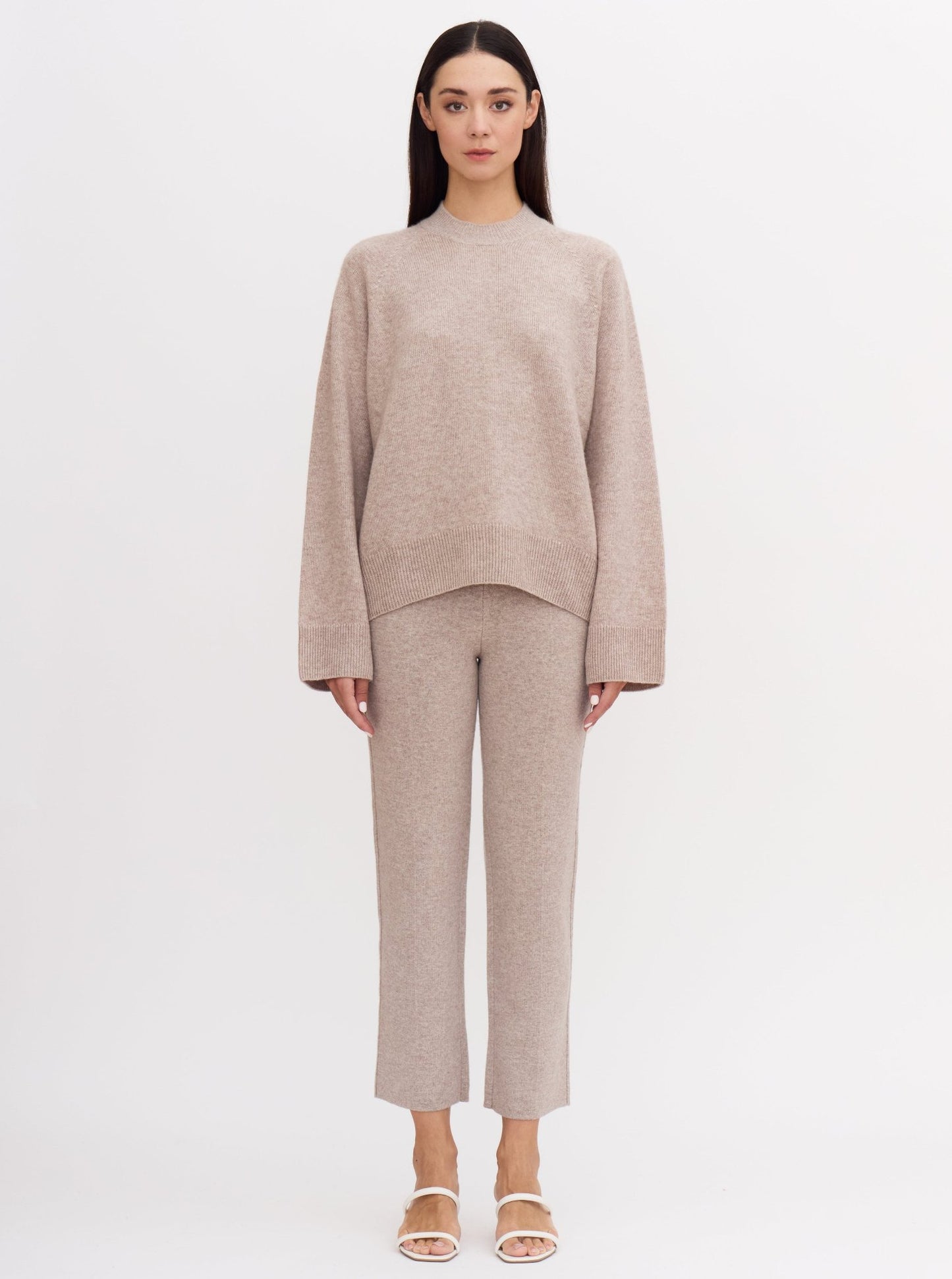 Front view of model wearing beige cashmere outfit: cropped cashmere suit pants and matching cashmere mock neck jumper.