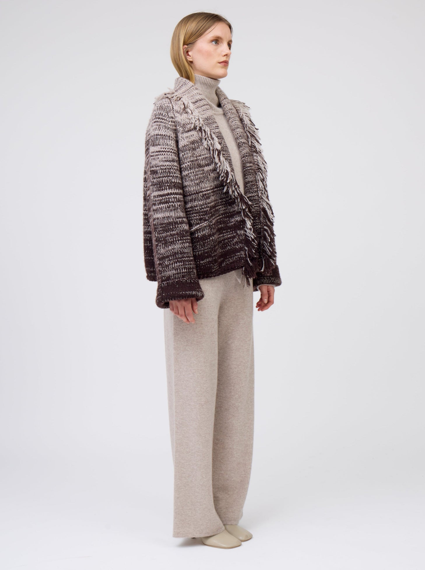 Model wears  gradient colour mix knitted short jacket in beige and dark brown and wide leg beige cashmere pants.