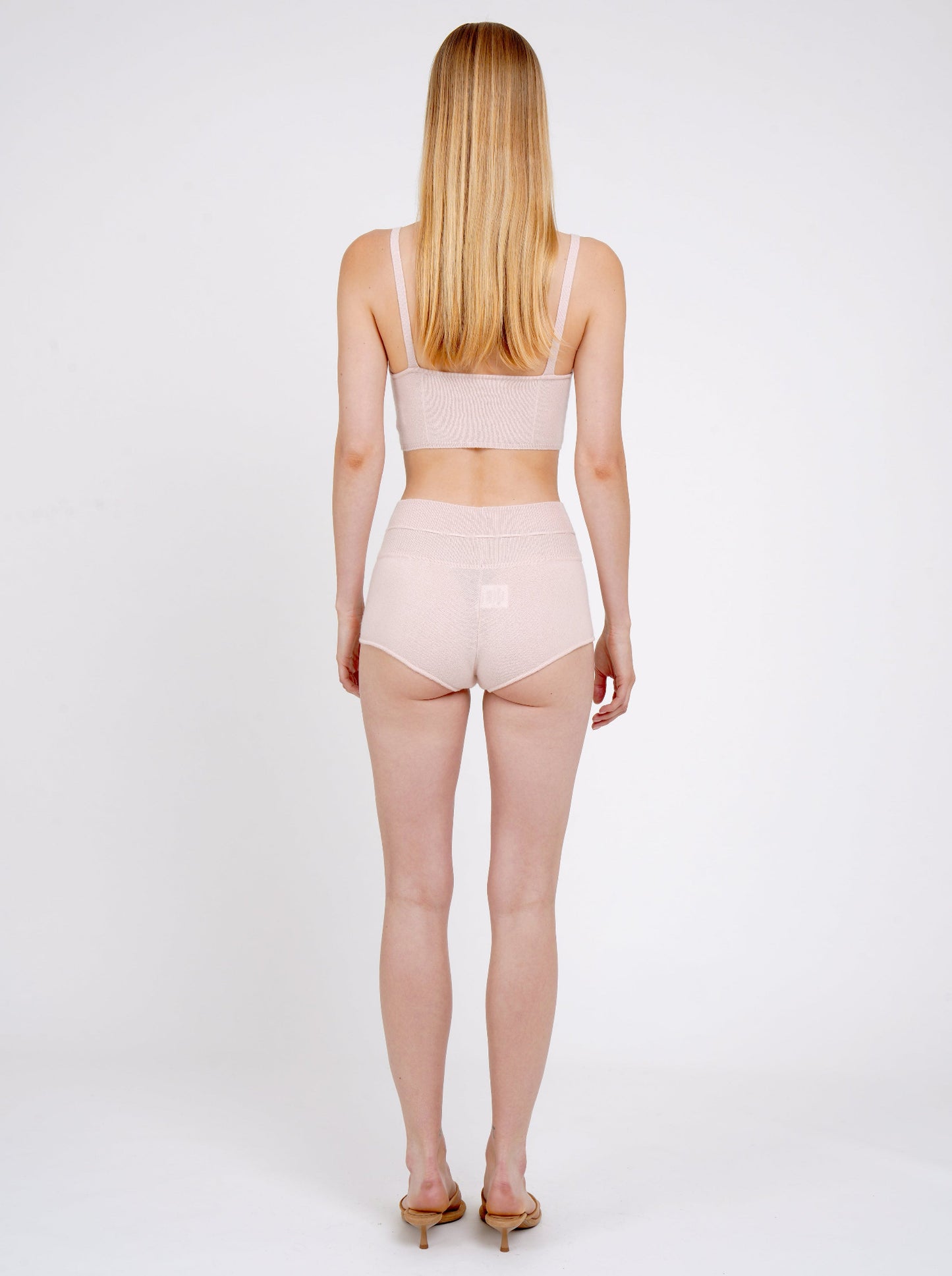 Back view model in pale peach cashmere shorts with drawstring waist and matching pale peach knit cropped bra top.