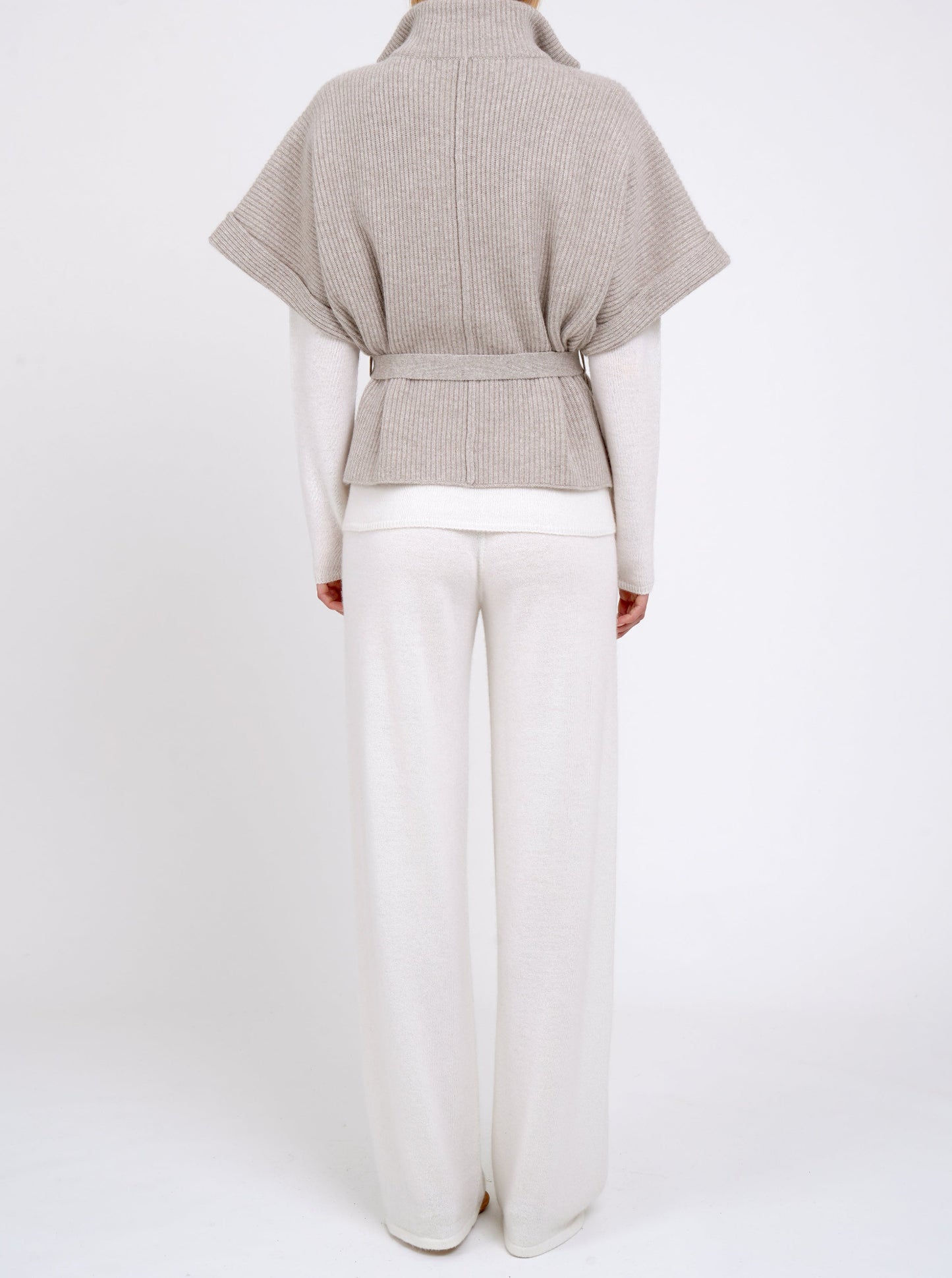 Back view model in pure white cashmere, wide leg pants worn with beige cashmere, ribbed knit, belted jacket.