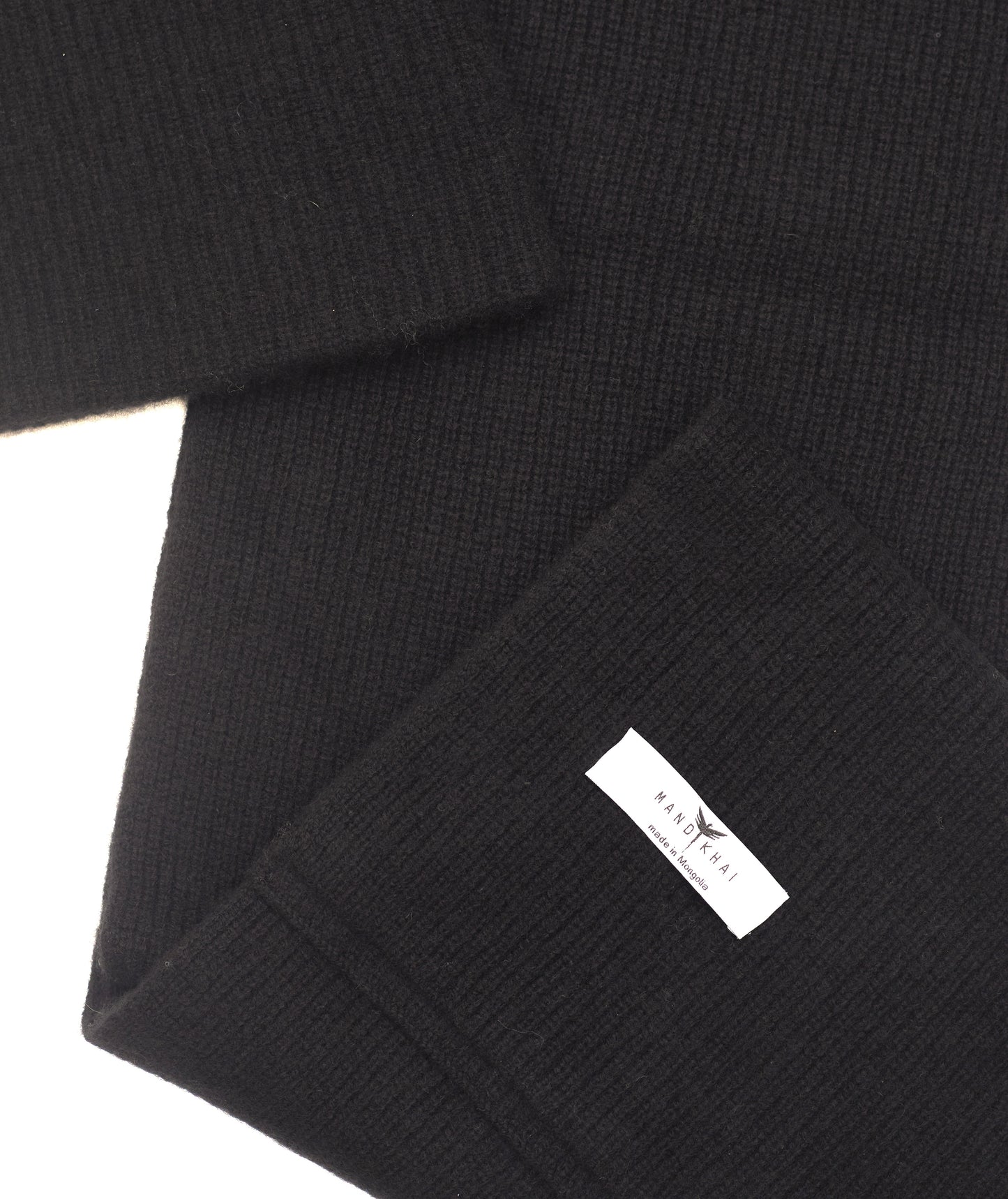 flat lay close up of black cashmere ribbed knit scarf and hat set with mandkhai label detail