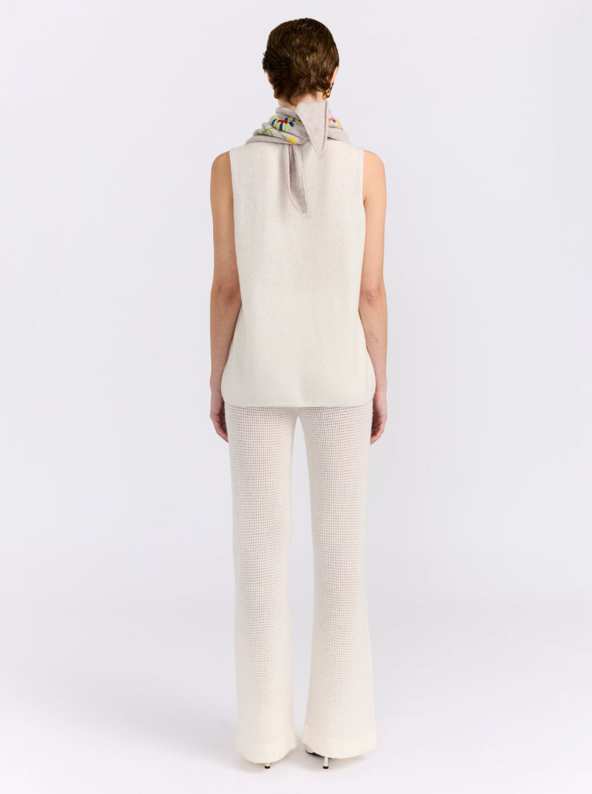 Model wearing the MANDKHAI New Beige embroidered triangle cashmere scarf styled around the neck.