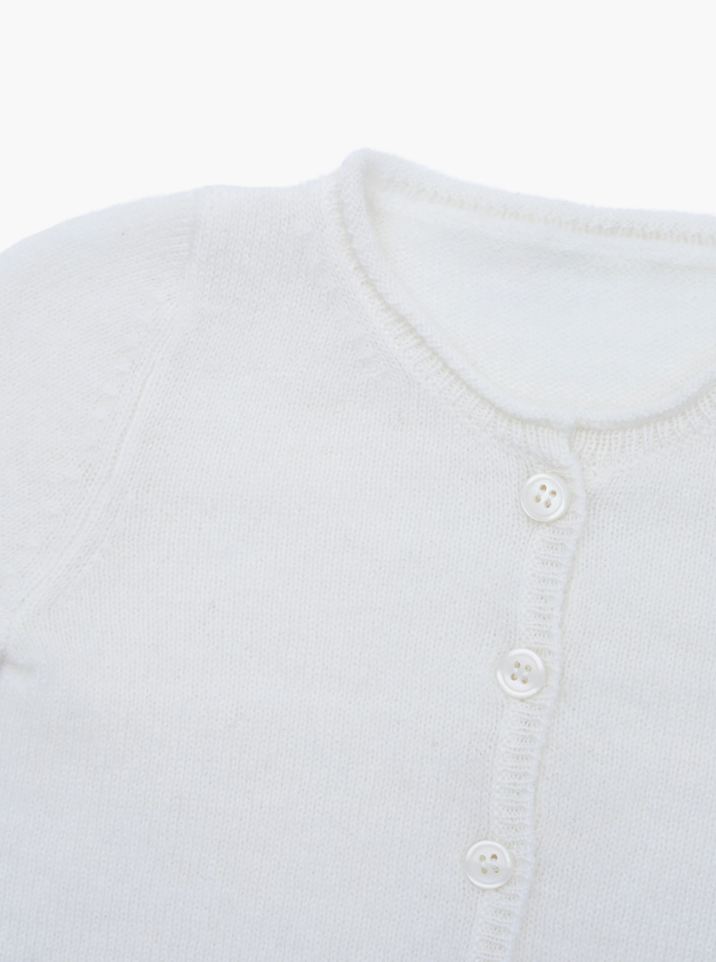 Close up button detail of the white baby cashmere cardigan