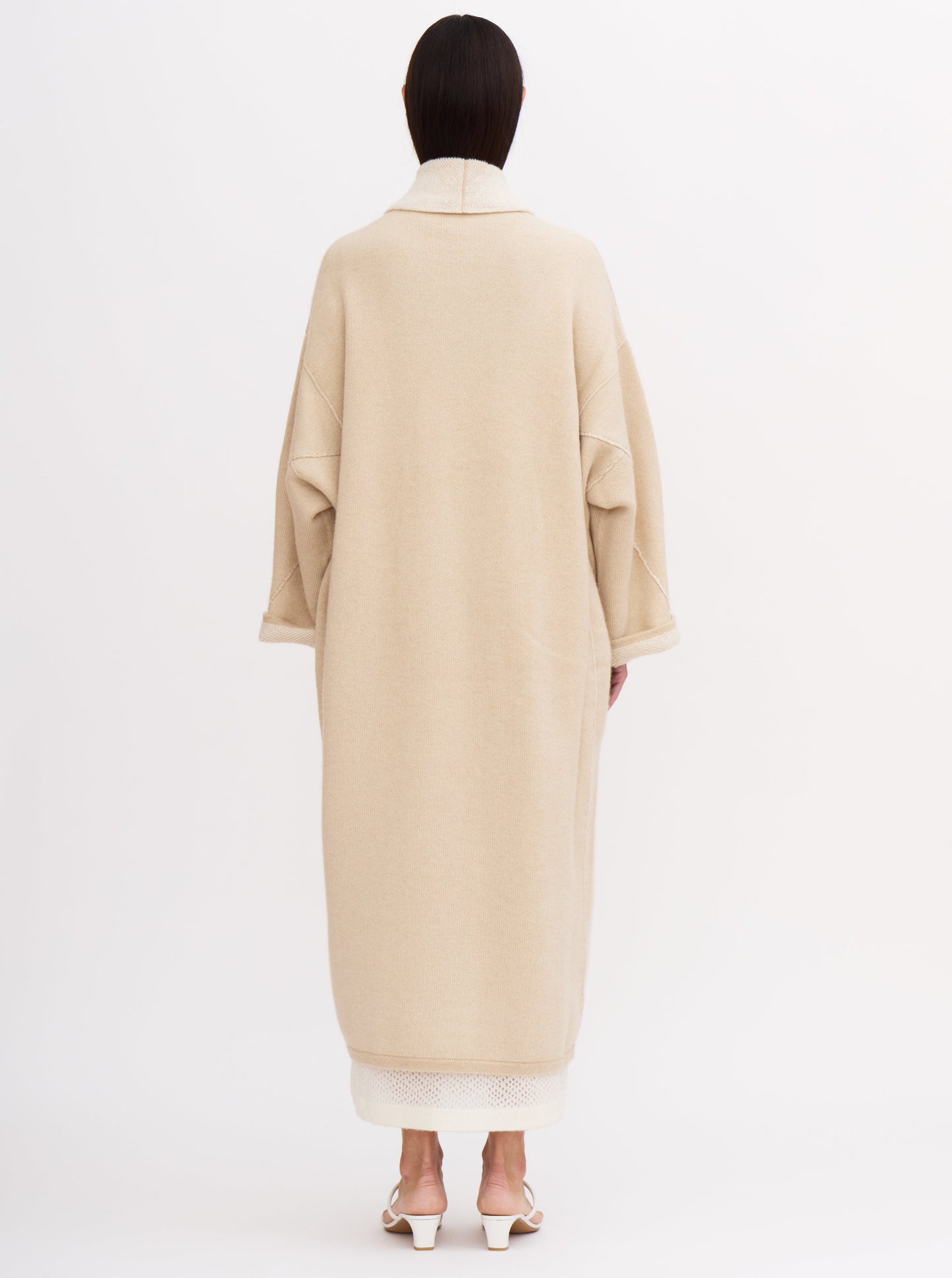 Long beige balloon-shaped cashmere coat with a two-tone design and relaxed fit, featuring a shawl collar and wide sleeves.