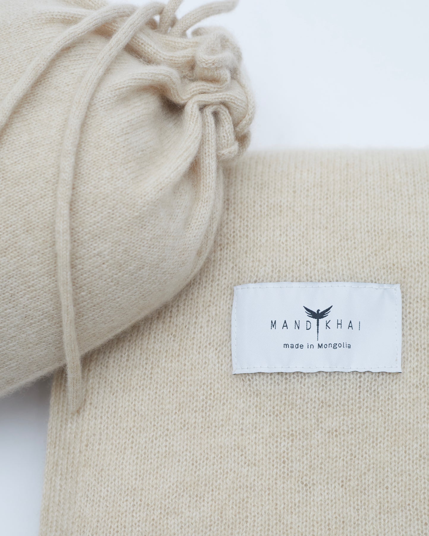 Close up flat lay of the Beige Cashmere Shawl With Travel Pouch featuring Mandkhai's label and the opening of the travel pouch 