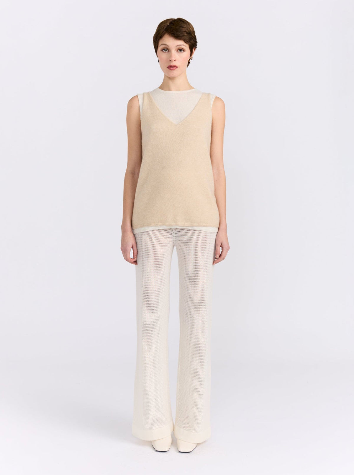 Model wearing the MANDKHAI beige and white double-layer cashmere vest with cream wide-leg trousers.