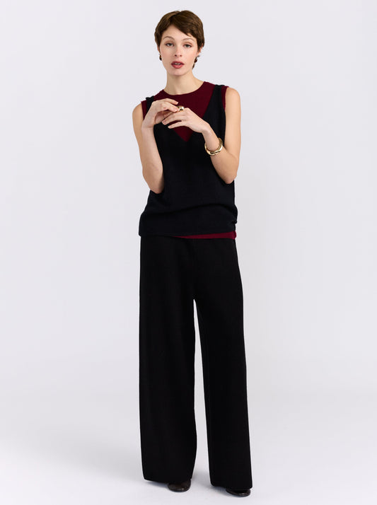 Front view of model wearing black wide leg trousers with black and burgundy cashmere knit sleeveless top