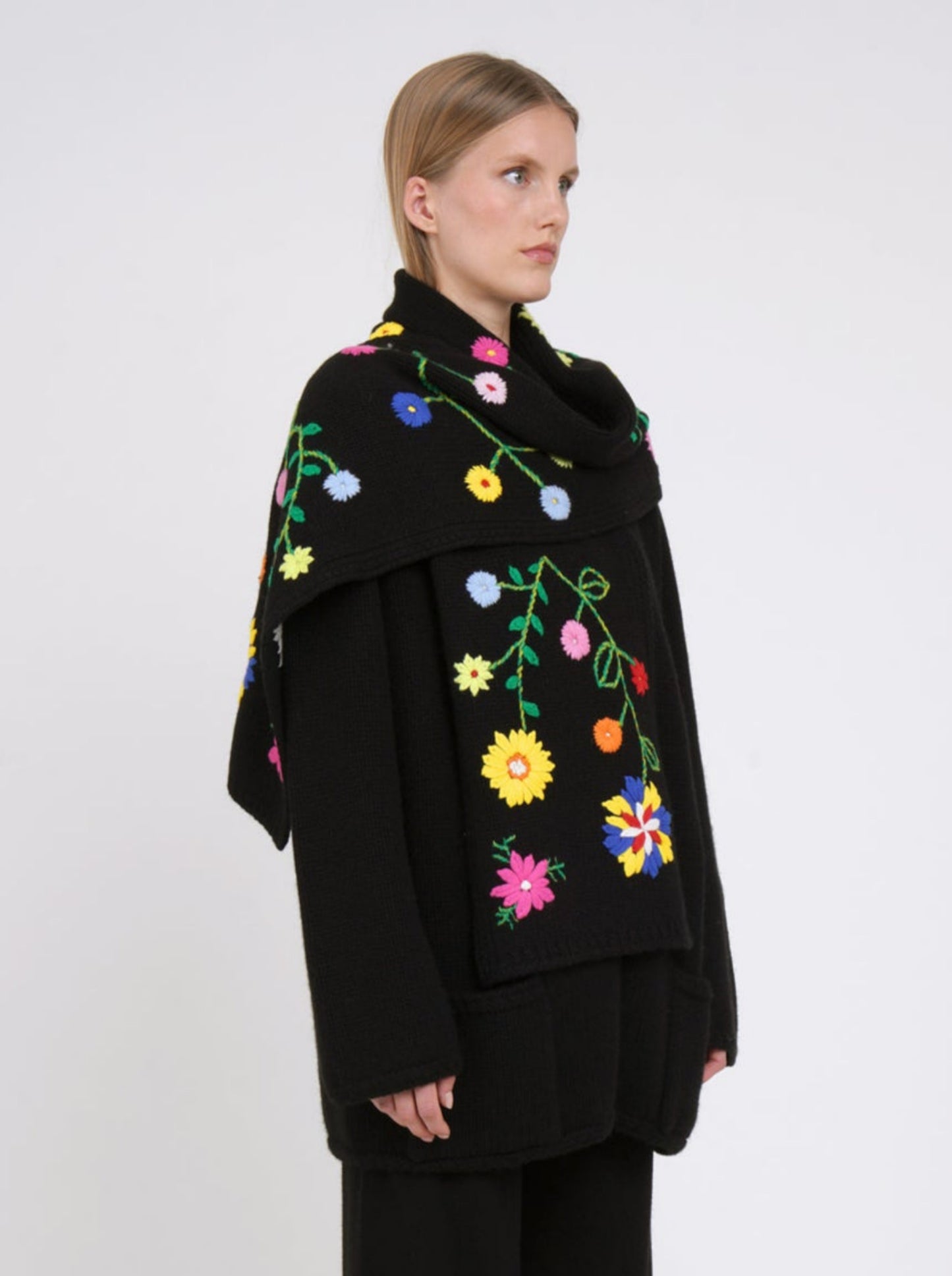 Side view cashmere hip length jacket with a detachable scarf, hand embroidered with bright coloured flowers; long sleeves, roll akc cuffs & patch pockets.