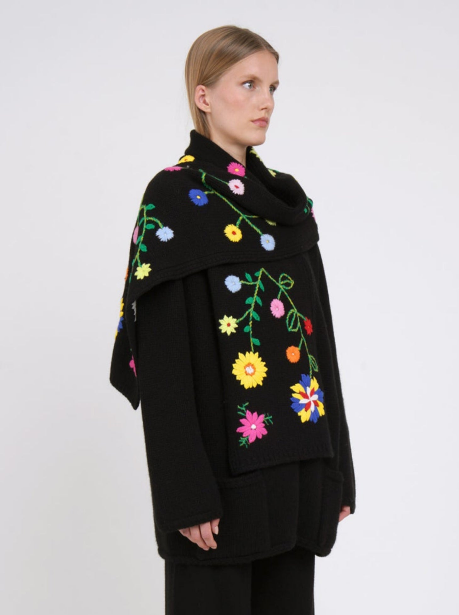 Side view cashmere hip length jacket with a detachable scarf, hand embroidered with bright coloured flowers; long sleeves, roll akc cuffs & patch pockets.