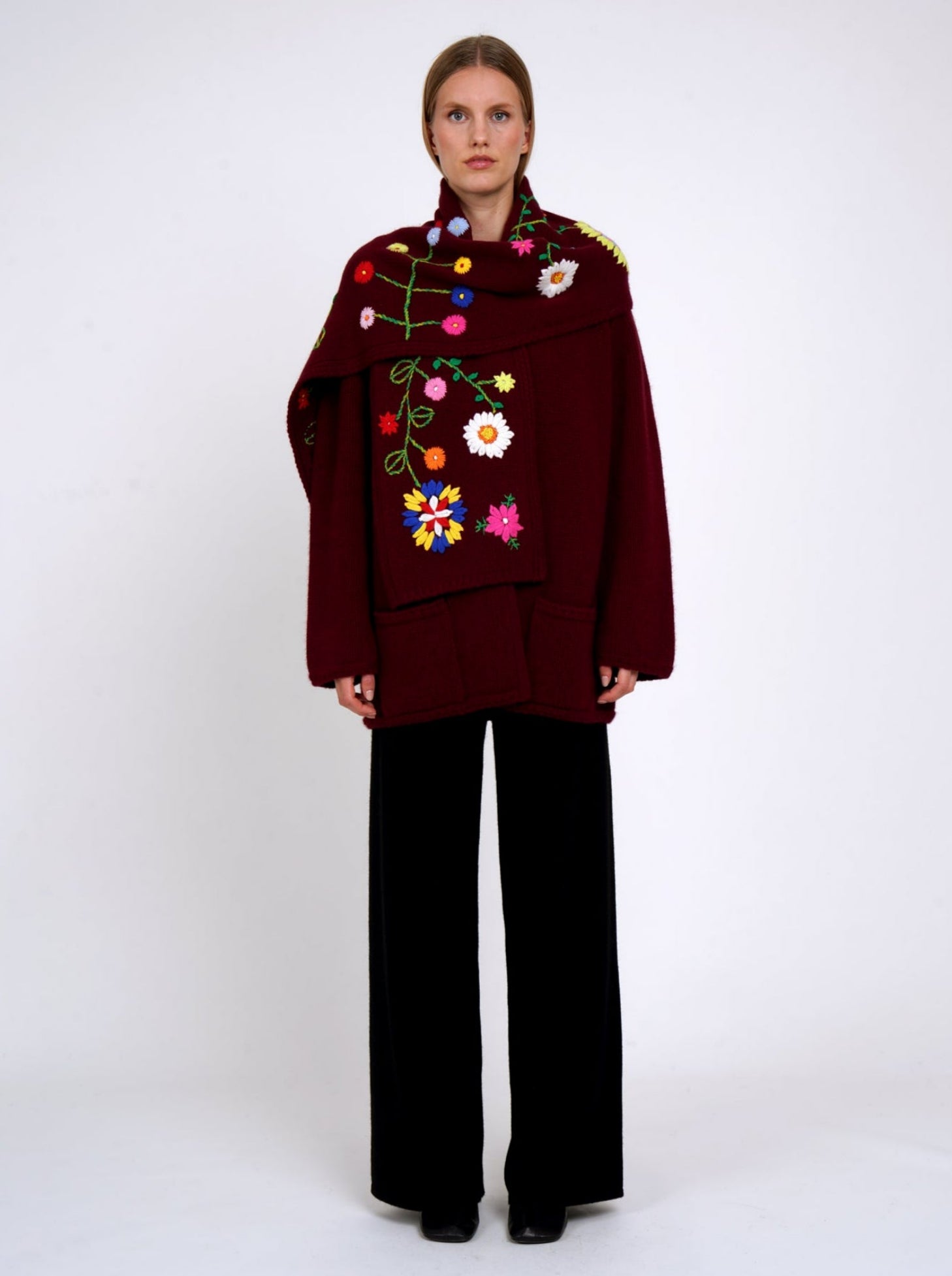 Burgundy cashmere hip length jacket with a colourful flower embroidered detachable scarf; worn with black cashmere trousers.