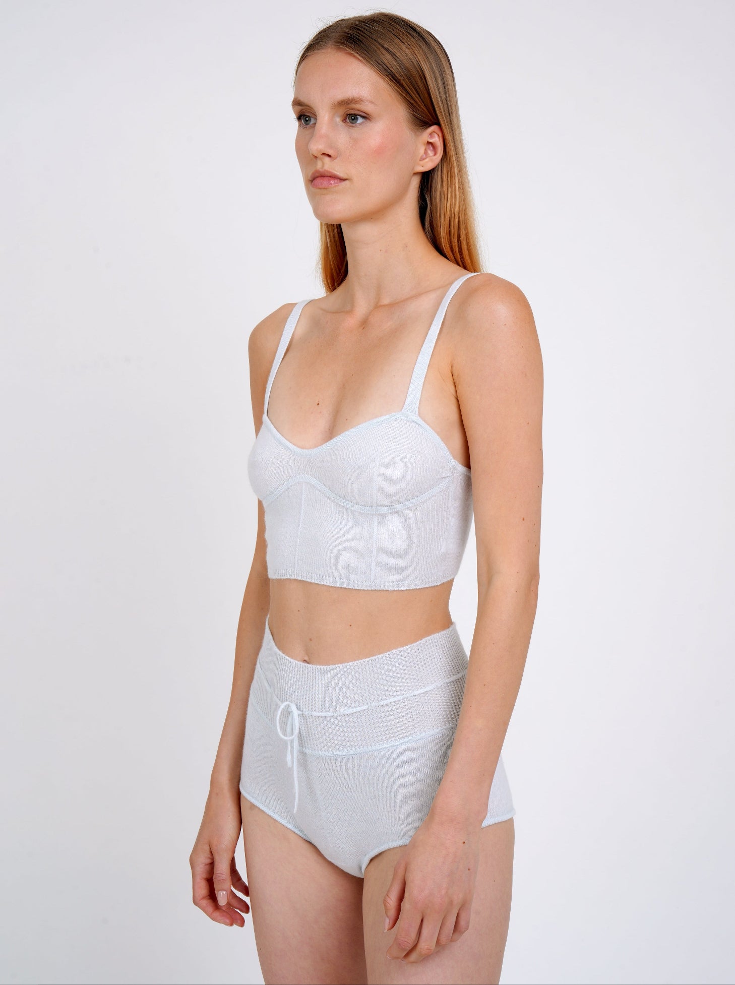 Close-up view model in pale blue knit cropped bra top and matching blue cashmere knit shorts with drawstring waist.