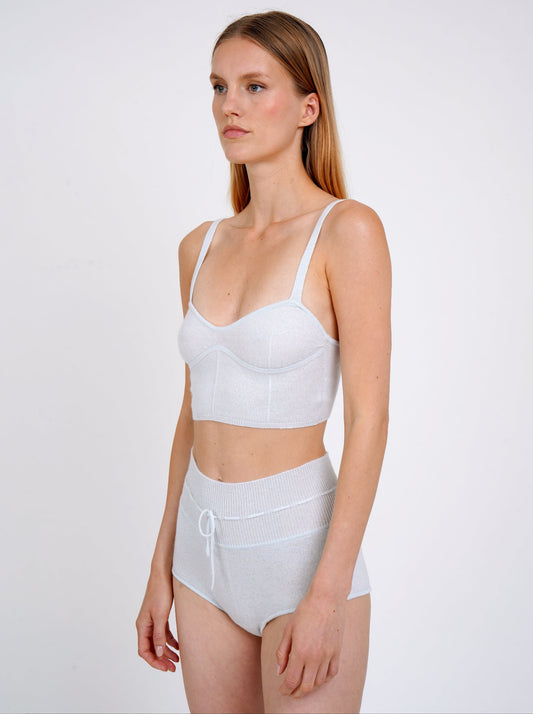 Side view close-up model in pale blue cashmere shorts with drawstring waist and matching pale blue knit  cropped bra top.