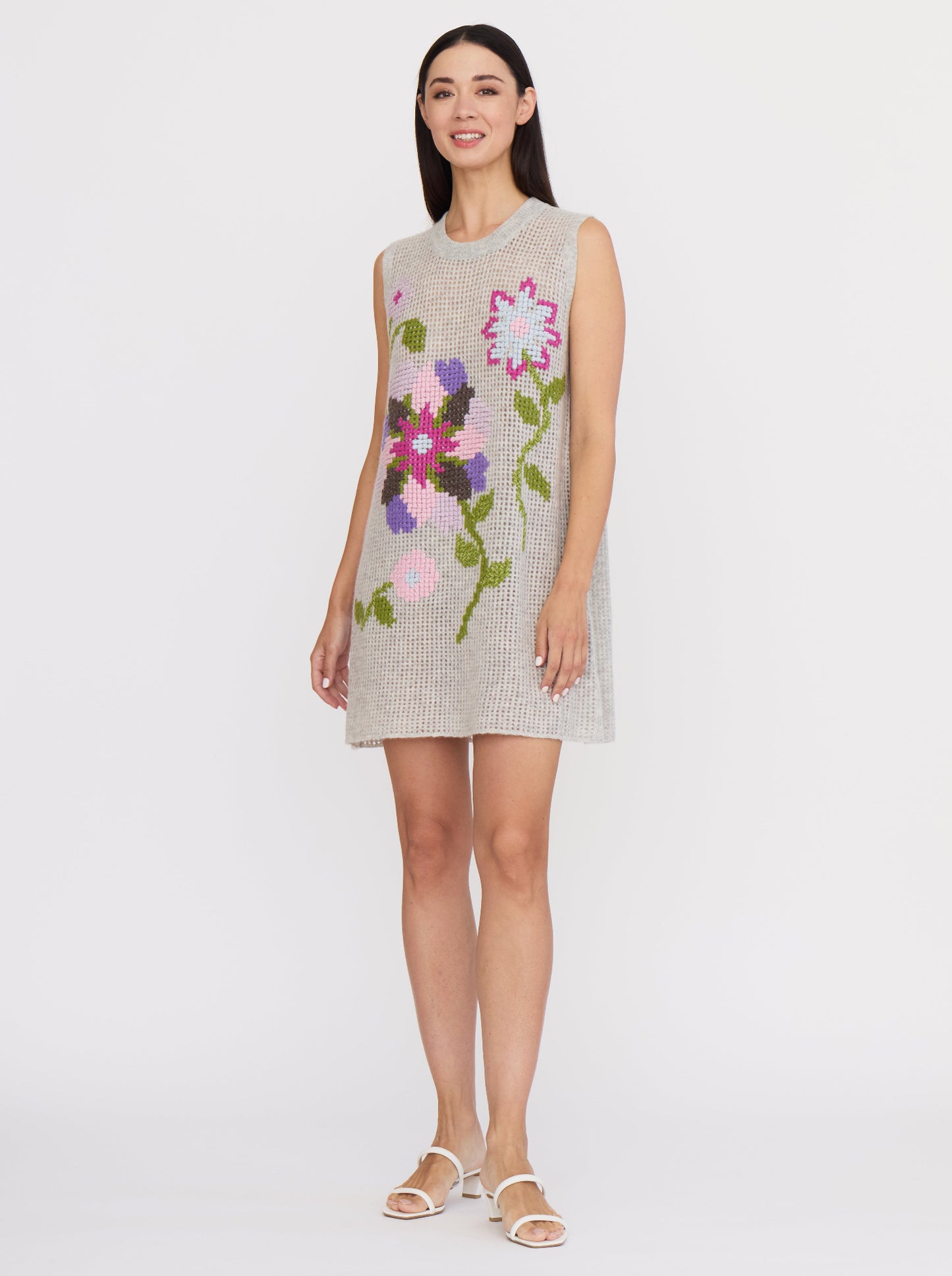 Grey net knit cashmere, sleeveless mini dress with floral cross-stitch embroidery in vibrant colours.