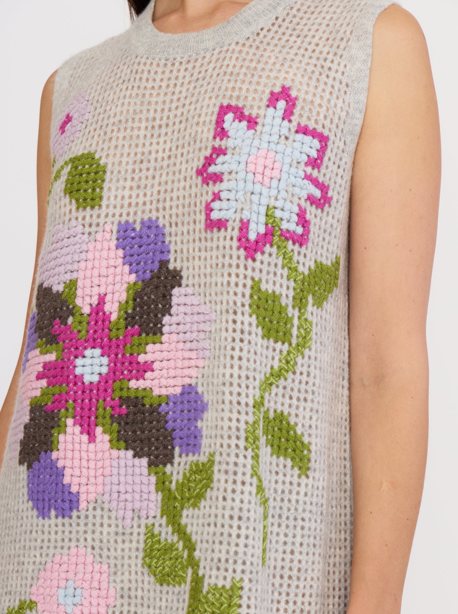 Close-up of grey cashmere sleeveless mini dress showing details of floral cross-stitch hand embroidery in vibrant cashmere colours.