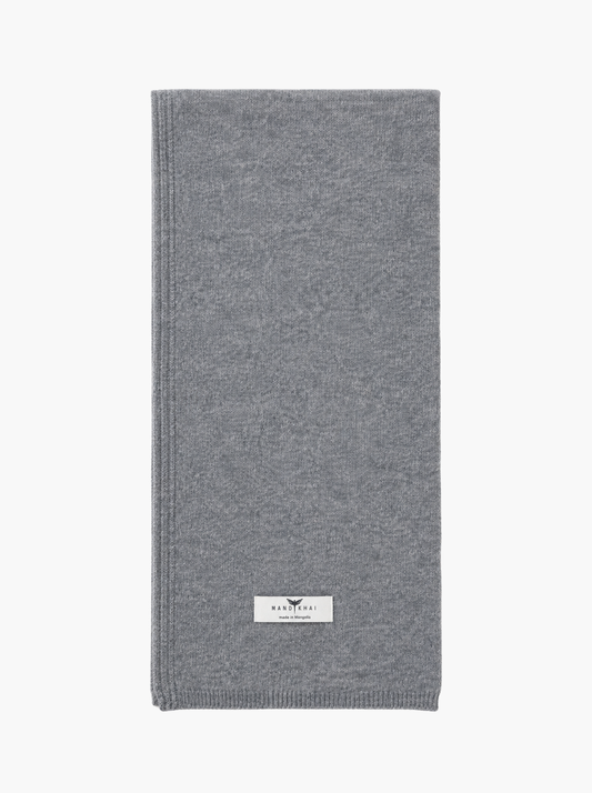 A folded gray knit scarf with a small white brand label near the bottom, shown against a plain white background.