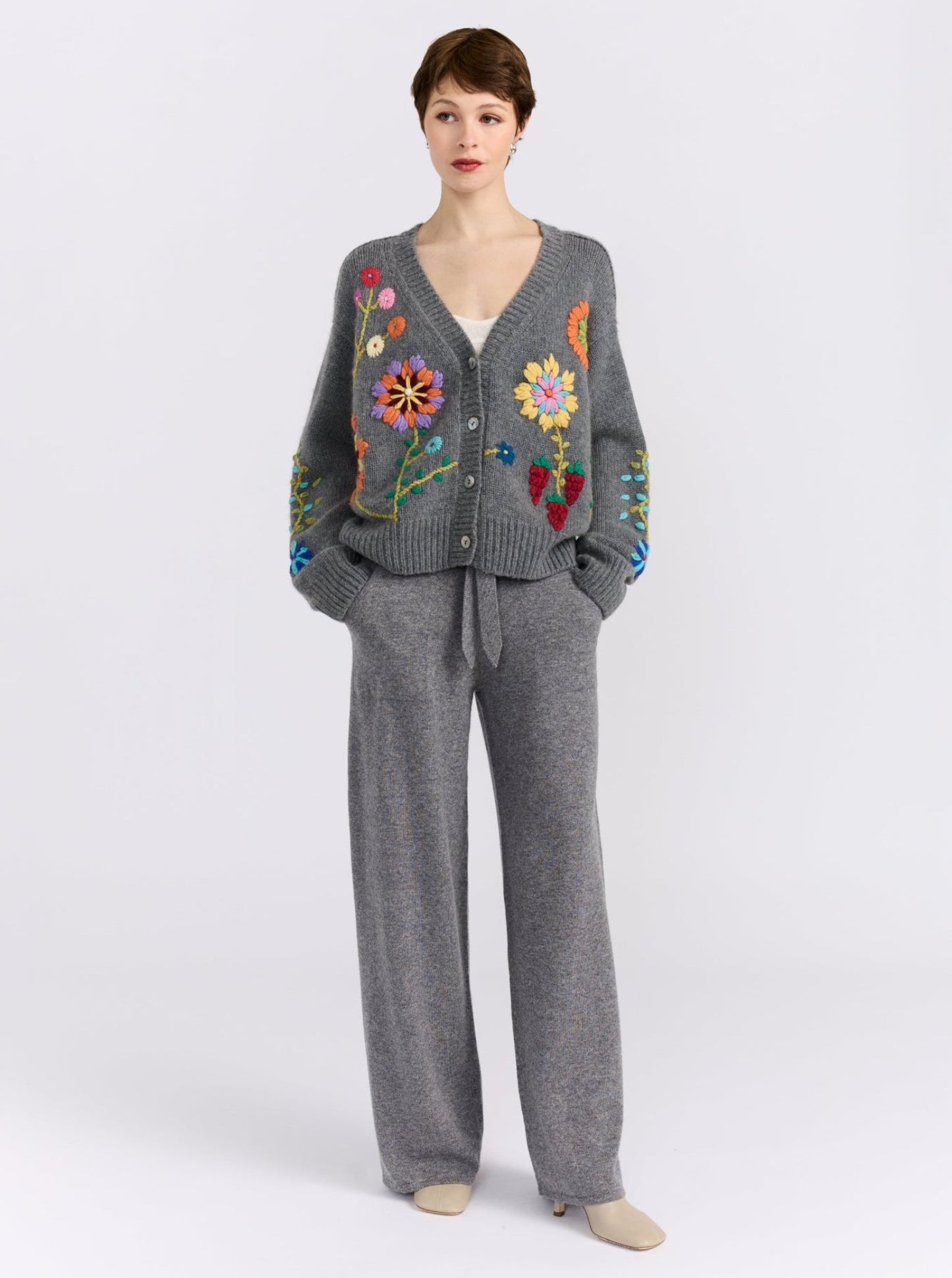 Model wearing a grey cashmere and wool cardigan with embroidery and matching grey pants 