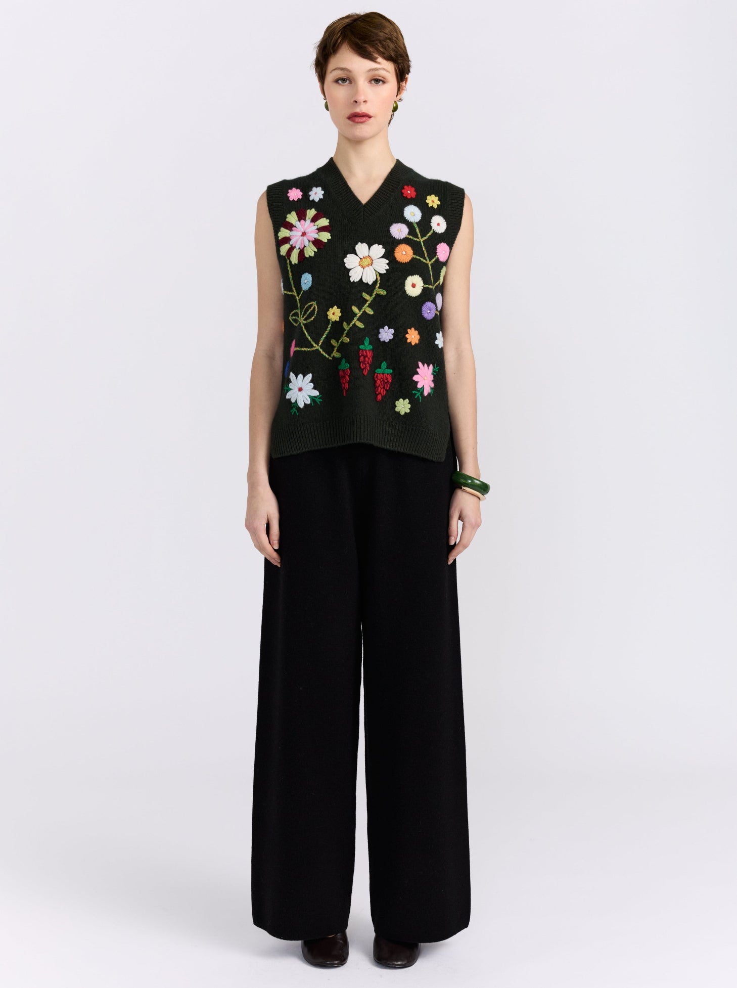 Khaki cashmere vest with hand-embroidered floral detailing, styled with black wide-leg trousers.