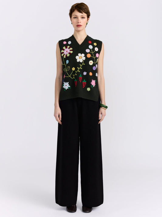Khaki cashmere vest with hand-embroidered floral detailing, styled with black wide-leg trousers.