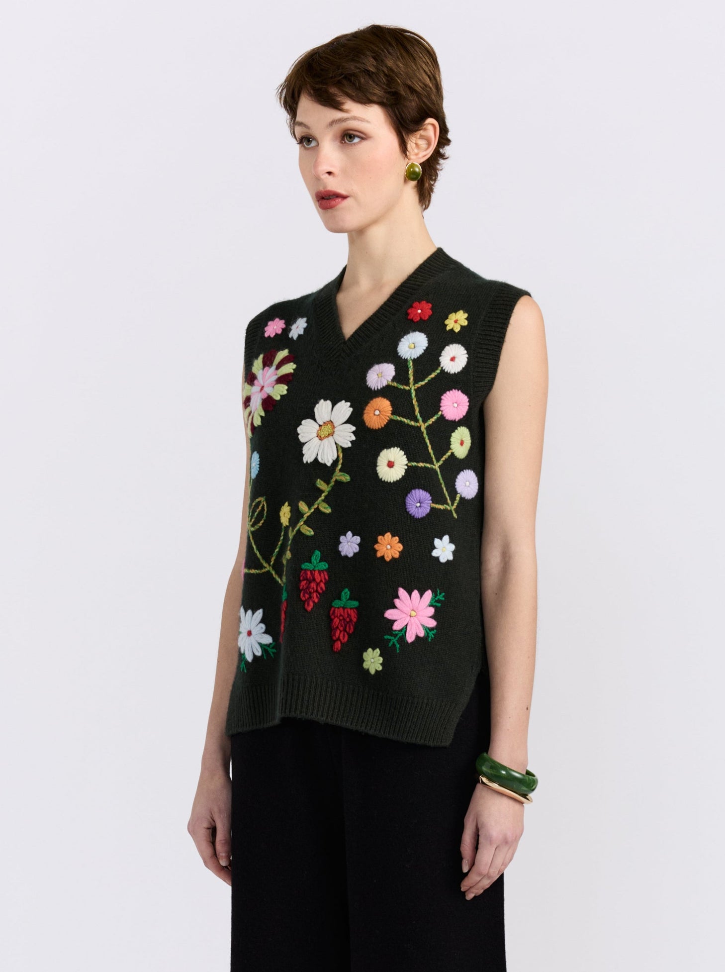 Khaki cashmere vest with hand-embroidered floral detailing, styled with black wide-leg trousers.