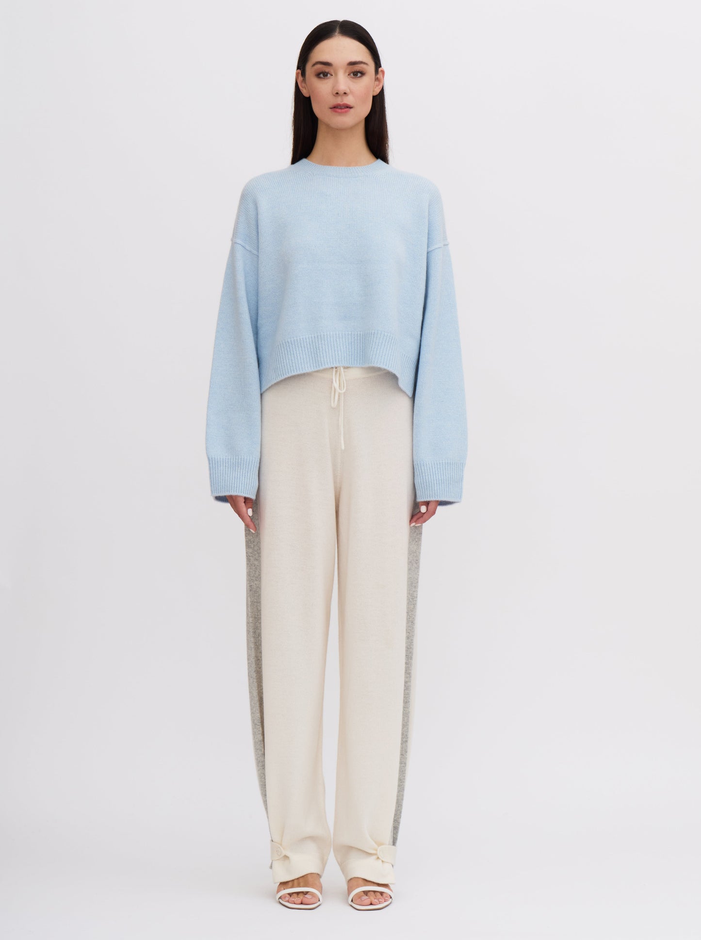 Light blue cropped cashmere sweater with cream trousers featuring grey side stripe.