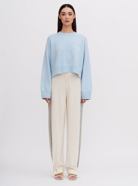 Light blue cropped cashmere sweater with cream trousers featuring grey side stripe.