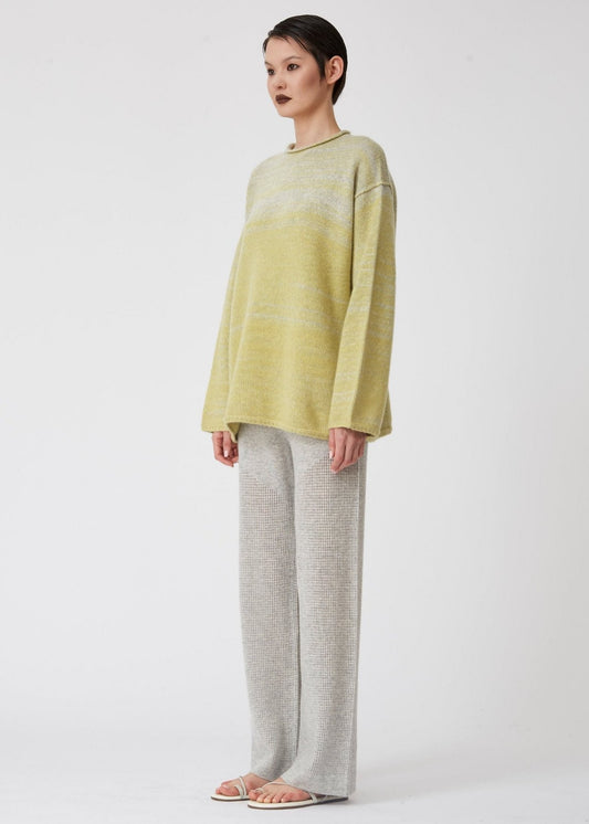 Model wearing light grey cashmere half net knit wide leg pants with relaxed fit lime green and grey long sleeve chunky knit cashmere jumper.