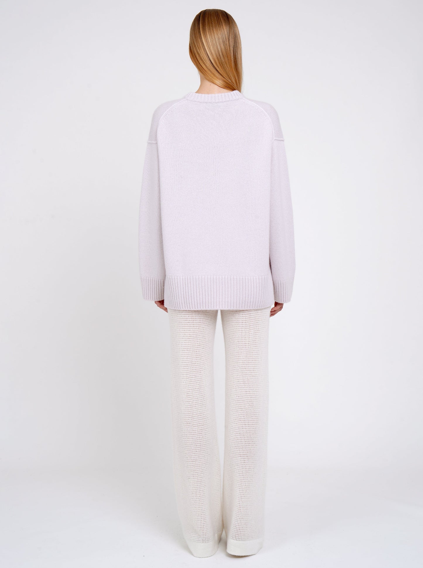 Back view model in pale purple long jumper with round neck, long sleeves and white cashmere knit pants.