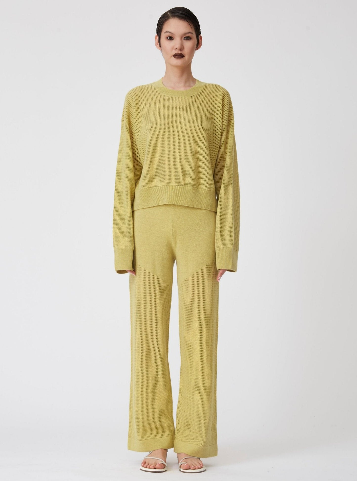 Front view of model wearing lime green long sleeve, light weight net-knit cashmere sweater with matching net knit wide leg pants.