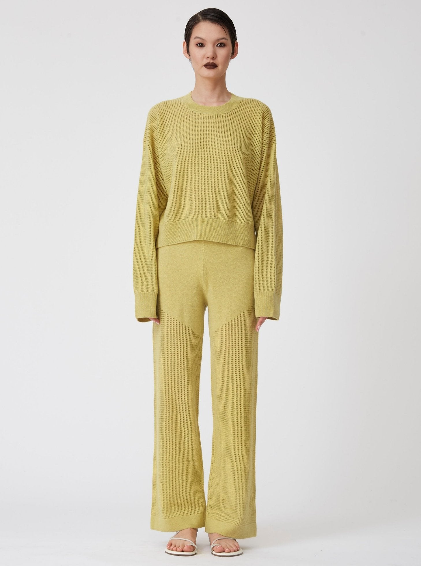 Front view of model wearing lime green long sleeve, light weight net-knit cashmere sweater with matching net knit wide leg pants.