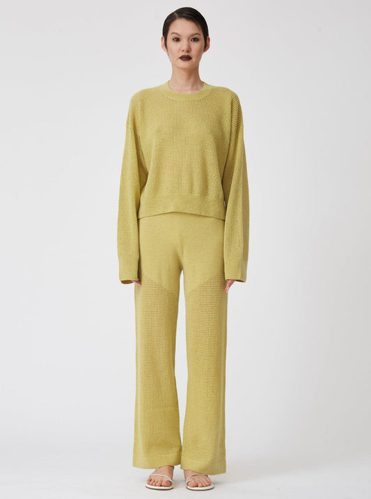 Front view of model wearing lime green long sleeve, light weight net-knit cashmere sweater with matching net knit wide leg pants.