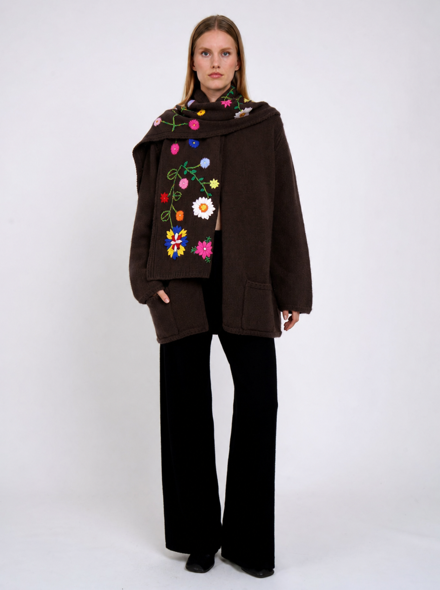 Woman wearing a brown coat with floral embroidery on a white background