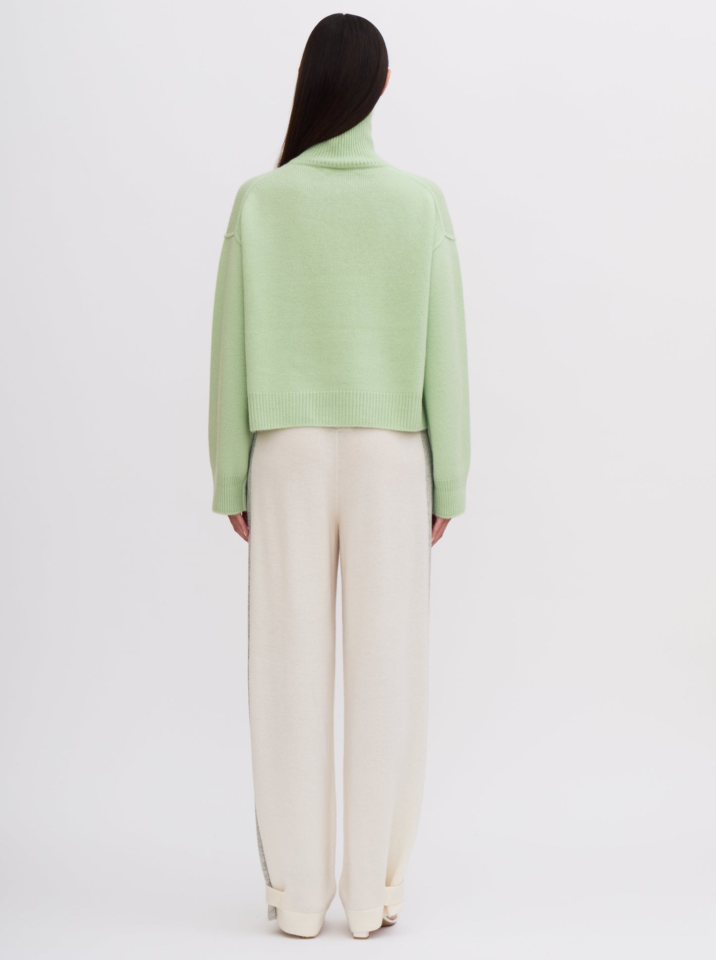 Back view Mint green cropped cashmere sweater with cream trousers featuring grey side stripe.