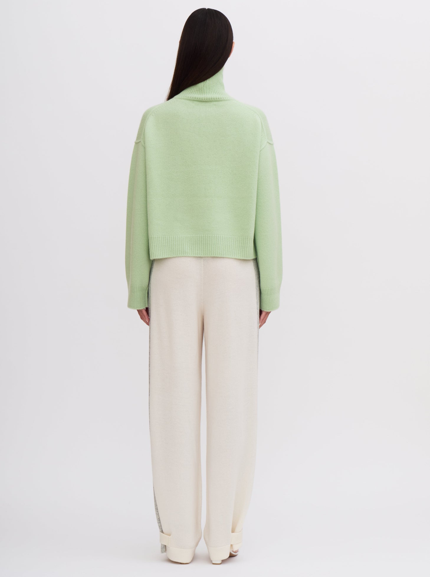 Back view Mint green cropped cashmere sweater with cream trousers featuring grey side stripe.