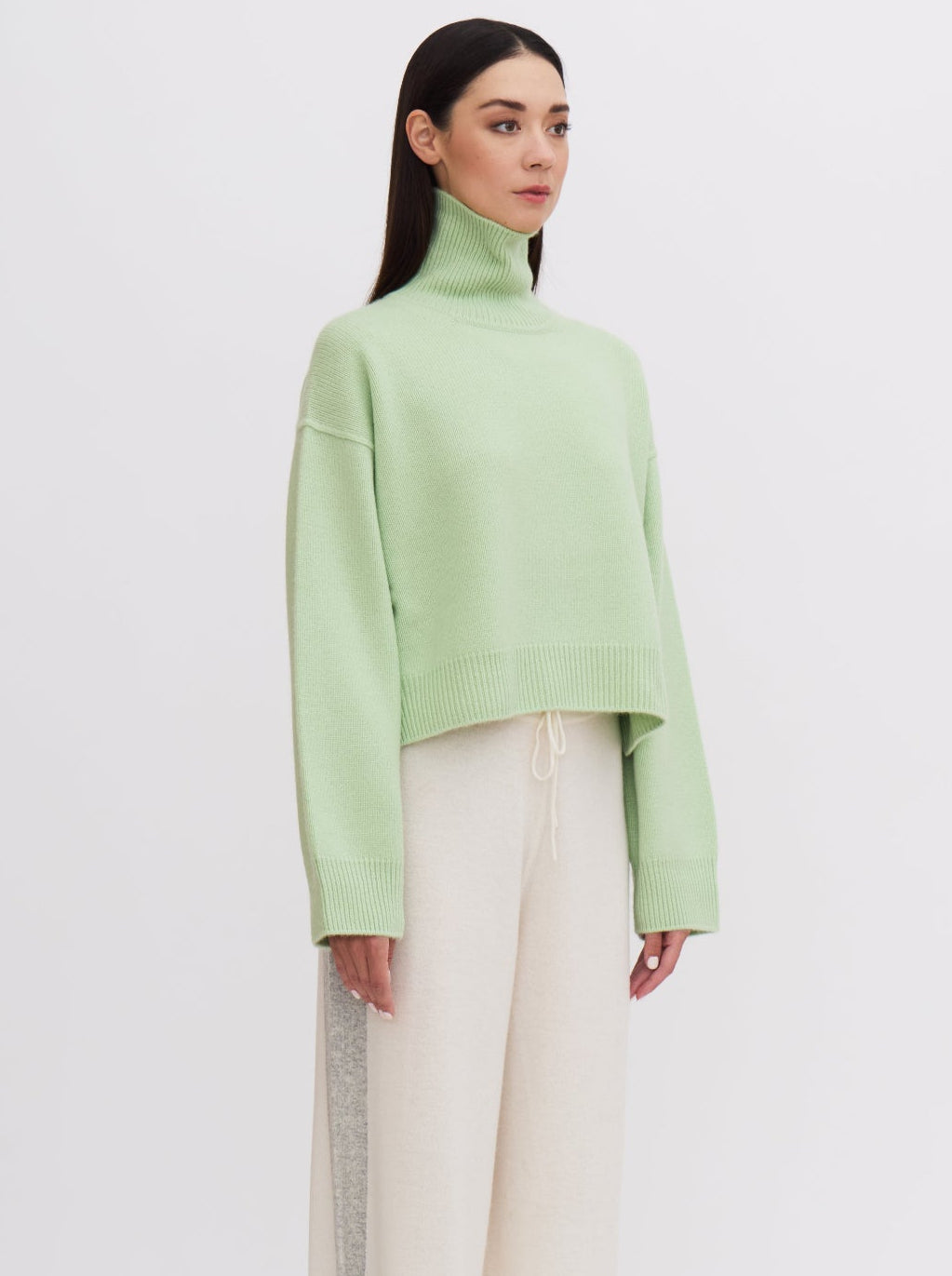 Side view Mint green cropped cashmere sweater with cream trousers featuring grey side stripe.