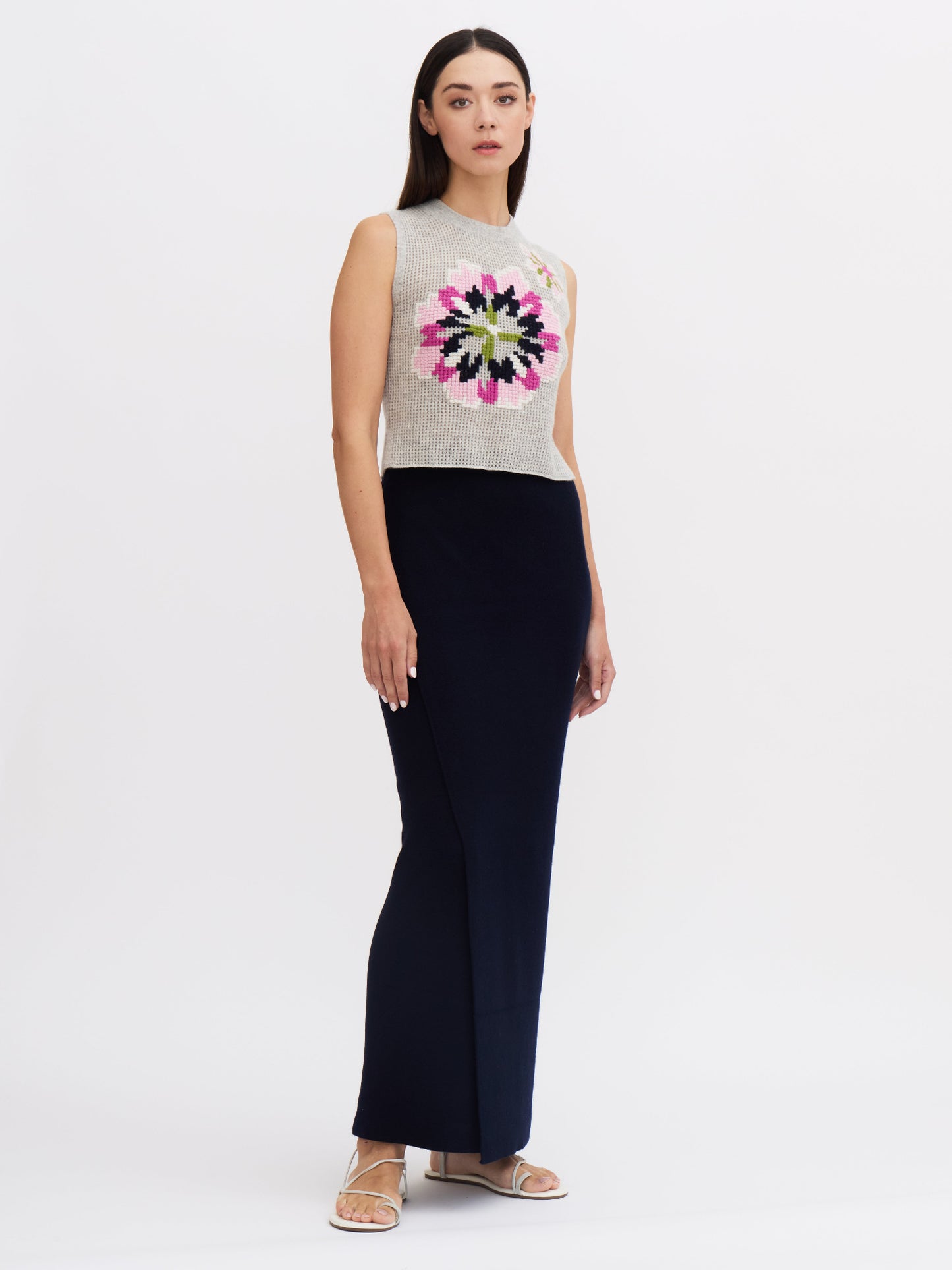 Front view of model wearing women's navy cashmere slim, dark  navy maxi-length wrap skirt and grey floral embroidered top.