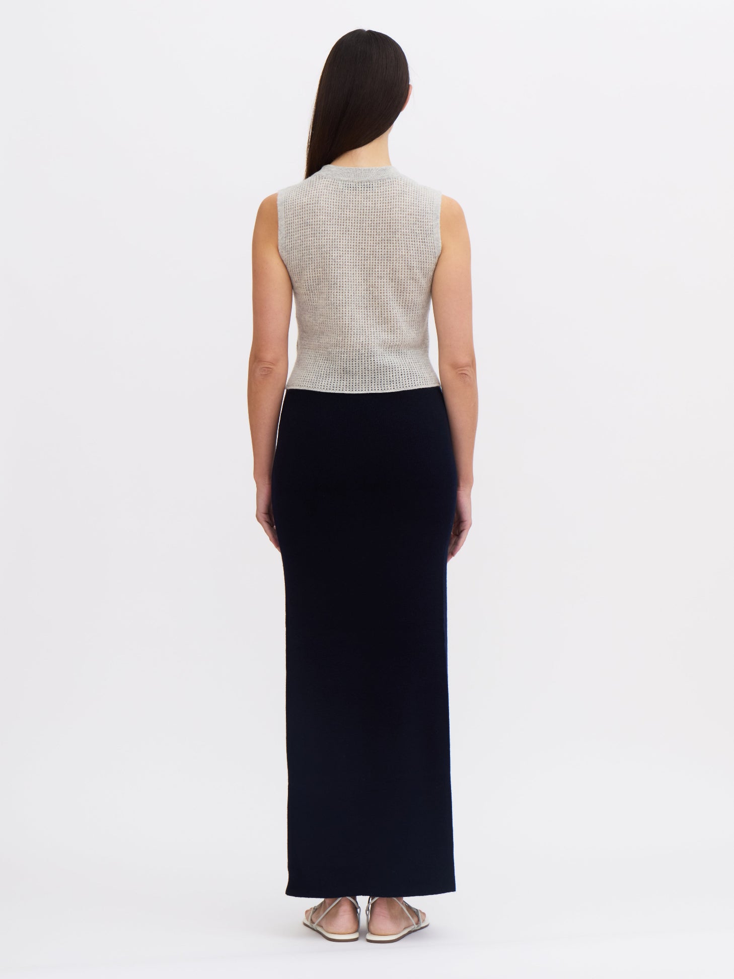 Back view of model wearing women's navy cashmere dark  navy maxi-length wrap skirt and grey cashmere top.