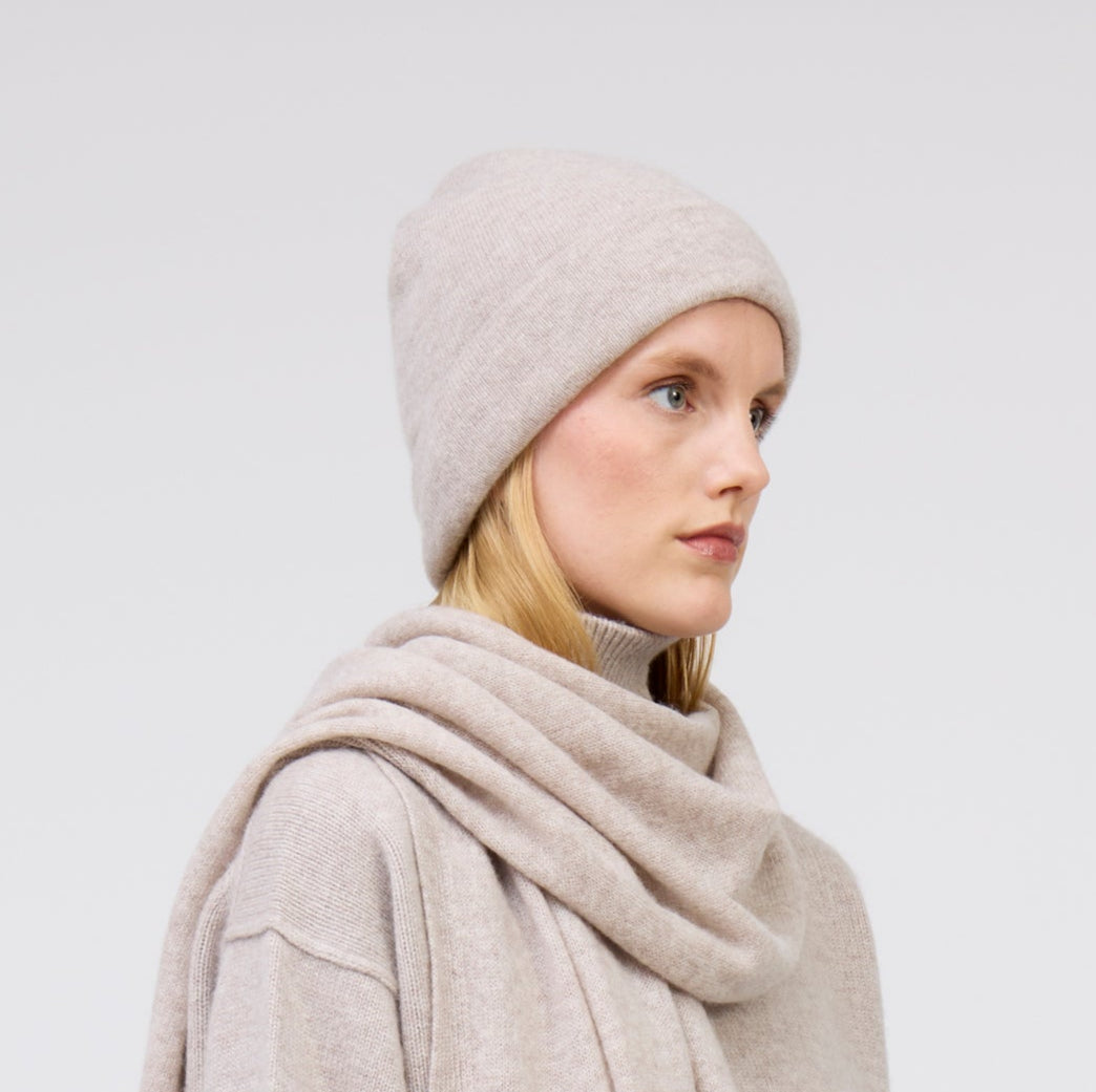 Close up of modal wearing pale beige cashmere beanie hat and matching beige cashmere scarf and jumper.