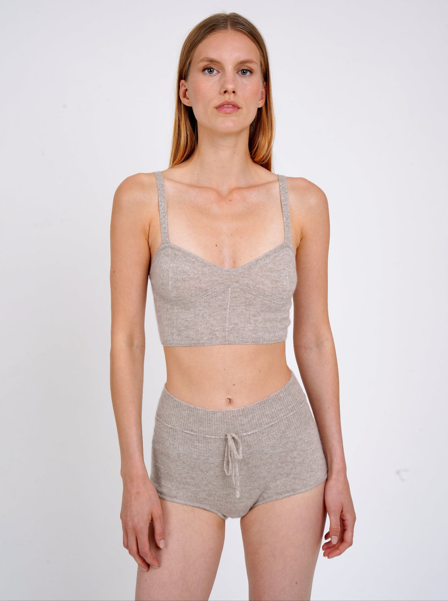 Model wears beige knit cropped bra top and matching beige cashmere knit shorts with drawstring waist.