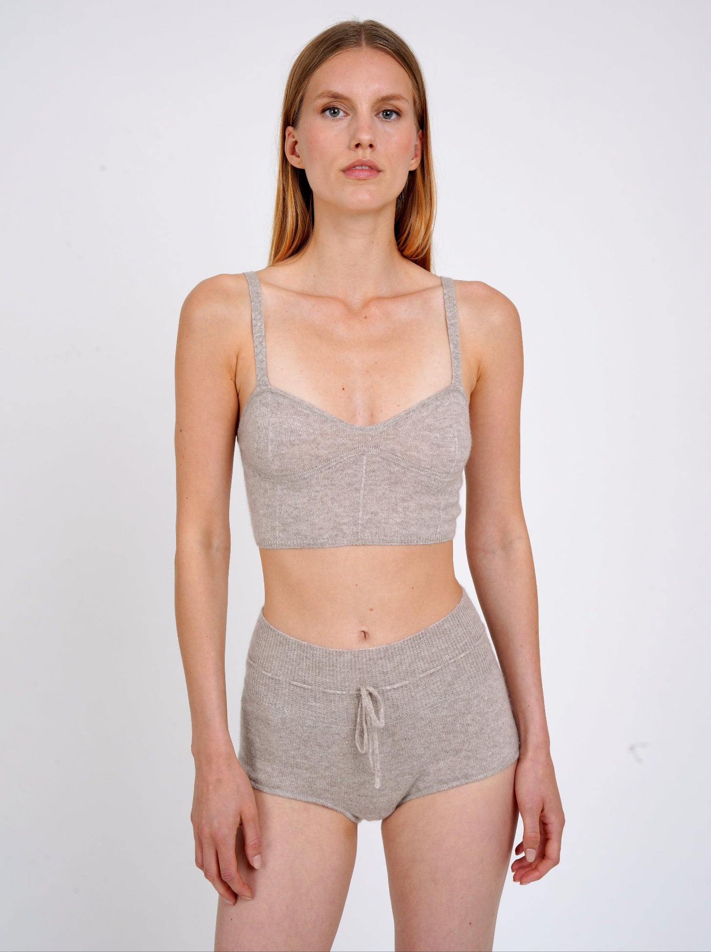 Model wears beige knit cropped bra top and matching beige cashmere knit shorts with drawstring waist.