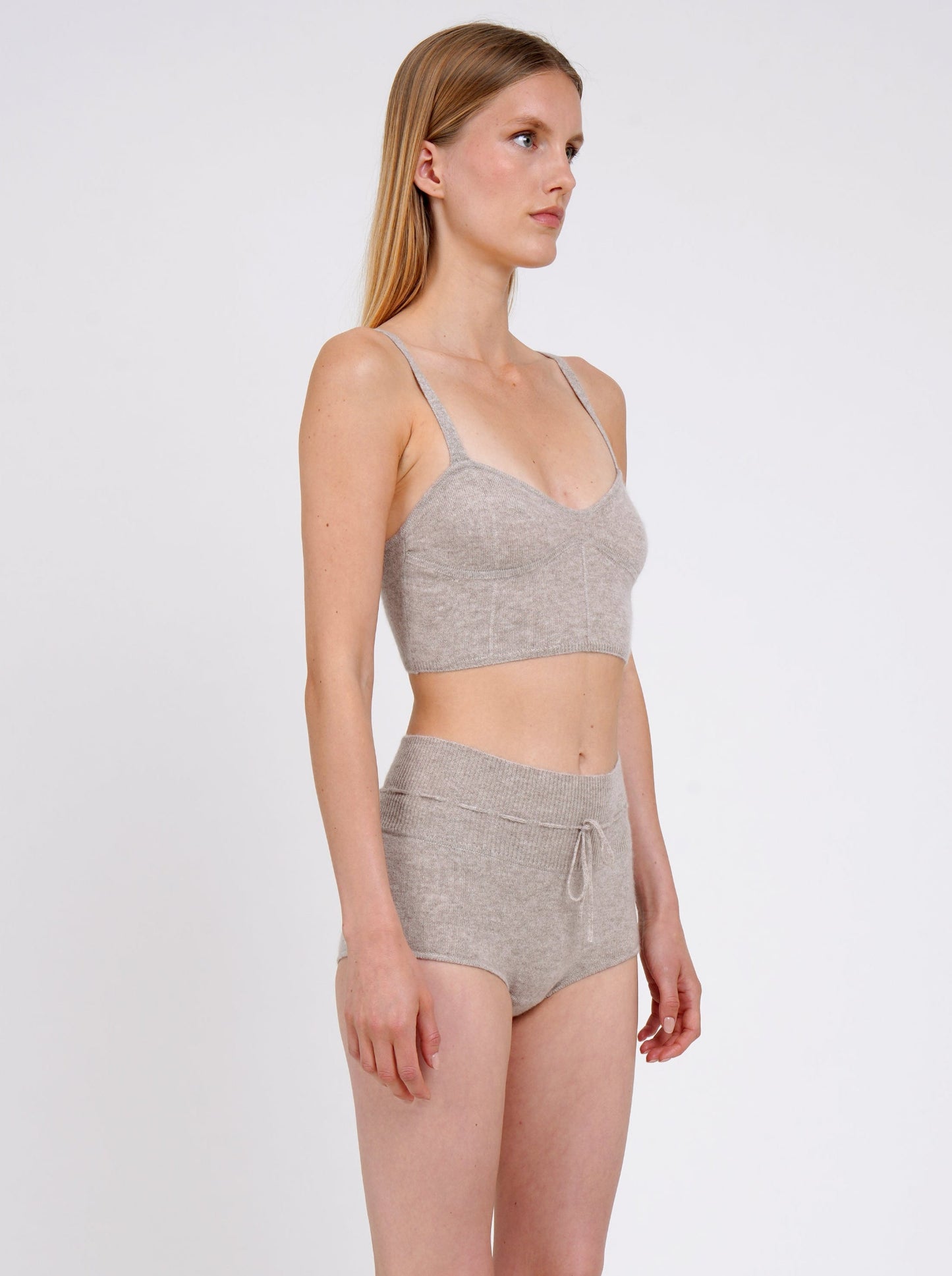 Side view model in beige knit cropped bra top and matching beige cashmere knit shorts with drawstring waist.