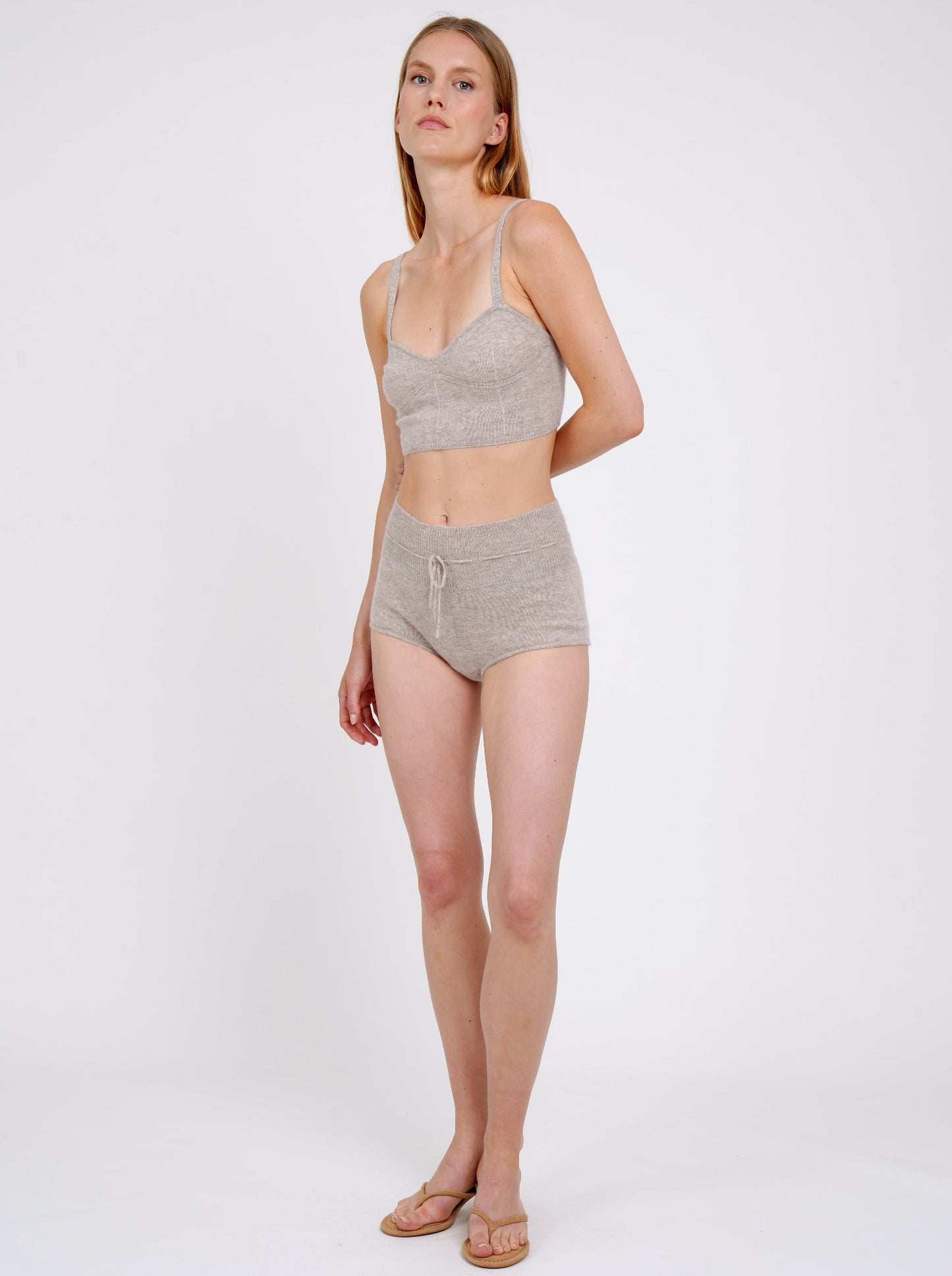 standing model wears beige cashmere shorts with drawstring waist and matching cropped bra top 