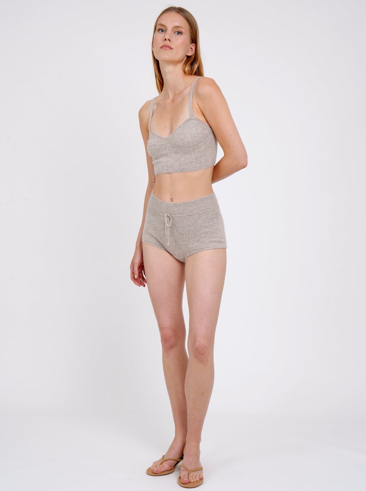 standing model wears beige cashmere shorts with drawstring waist and matching cropped bra top 